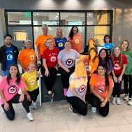Smiling dental team members in brightly colored tee shirts
