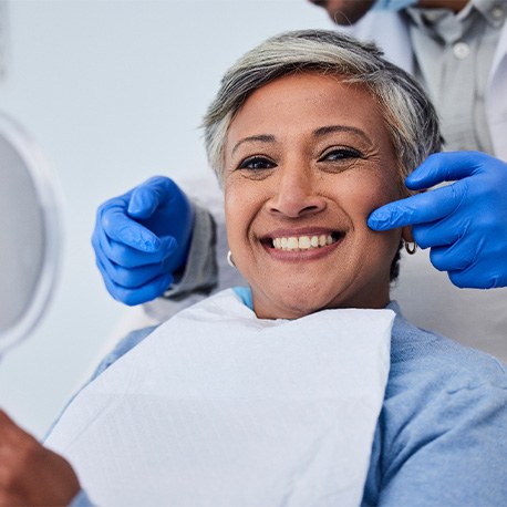 smiling patient with the dentist’s hands near her mouth